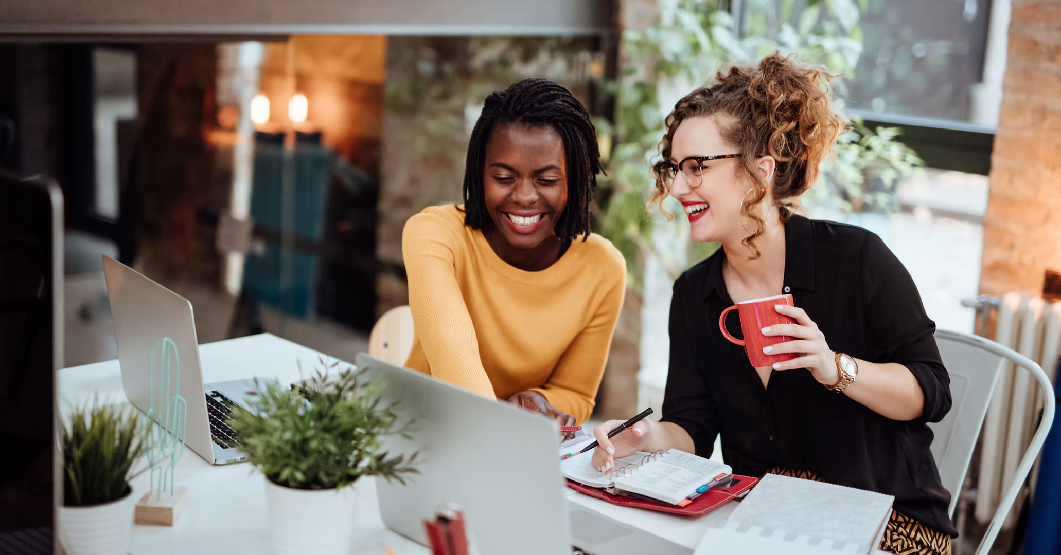 Two women smiling and working together at a table